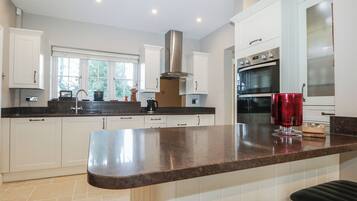 A modern kitchen with white cabinets, a stainless steel range hood, and a large island with a red candle.