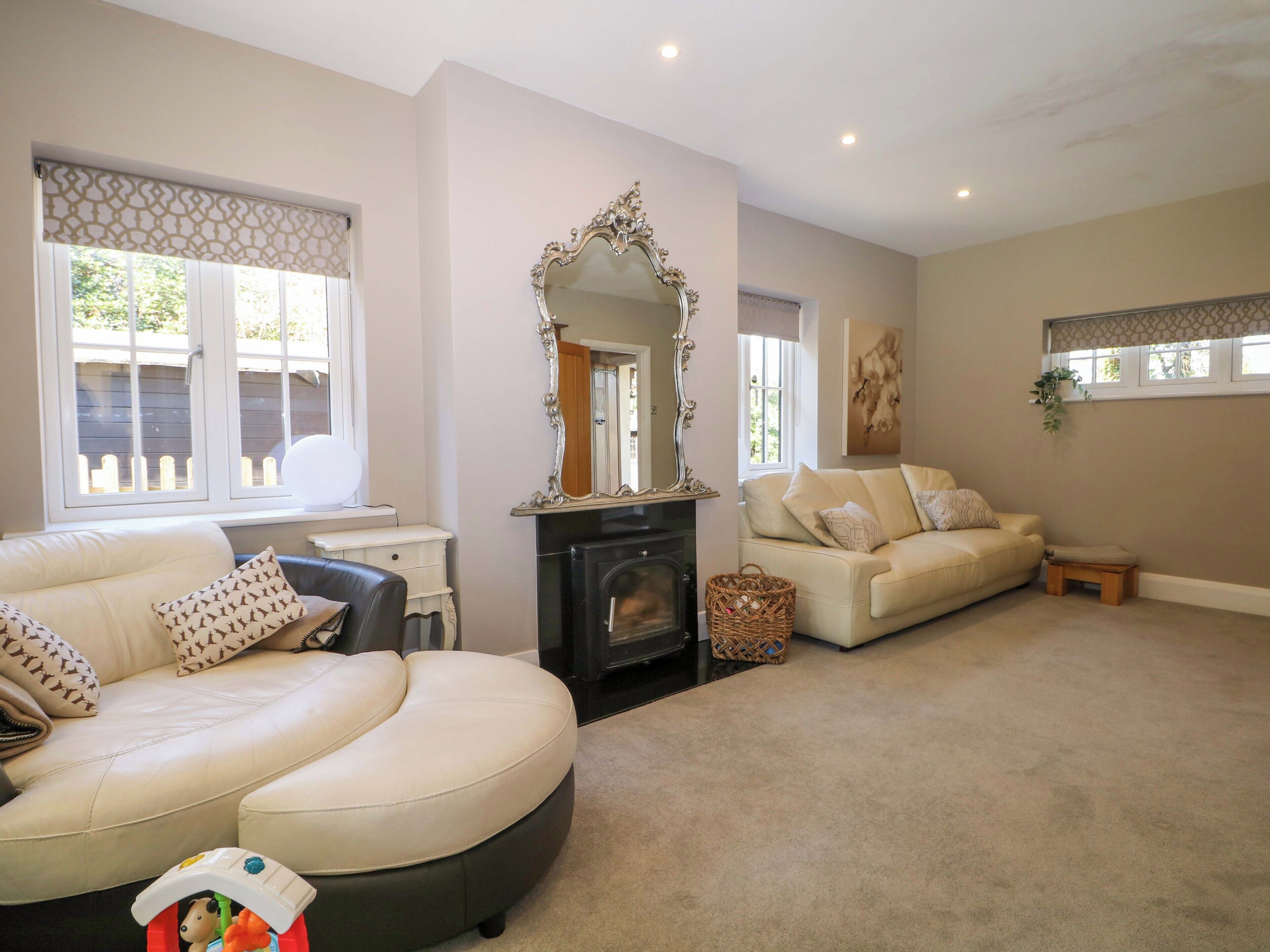 A living room with a fireplace, two sofas, a large mirror, and a window with a view of the outside.