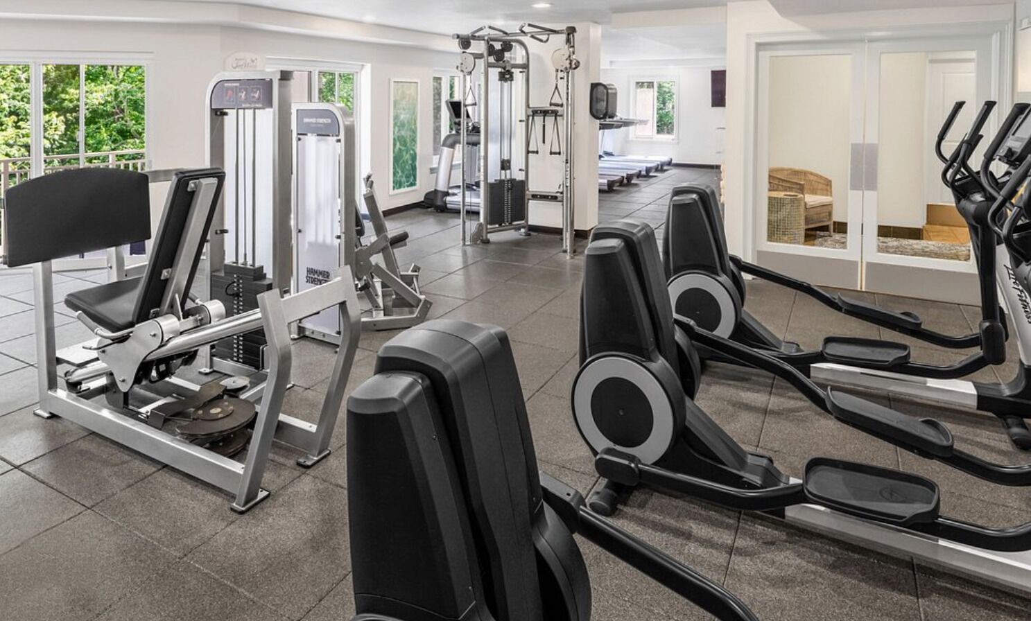 Ein Fitnessstudio mit Laufbändern, Krafttrainingsgeräten und Rudergerät.