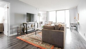 A modern living room with a grey sofa, a flat-screen TV, a coffee table, and a patterned rug. - Landing Apartments Fort Wayne - East Central (Fort Wayne)