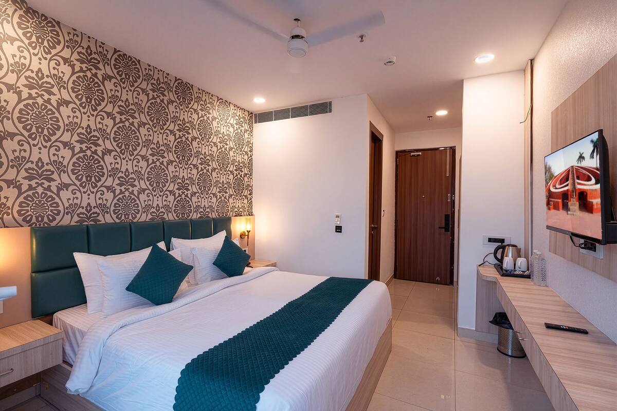 Una habitación de hotel moderna con una cama grande, televisión, escritorio y pared con un diseño estampado.