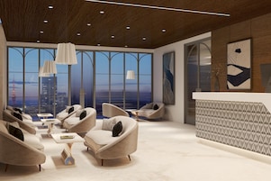 Un salón moderno con sofás, mesas y vistas a la ciudad a través de grandes ventanales.