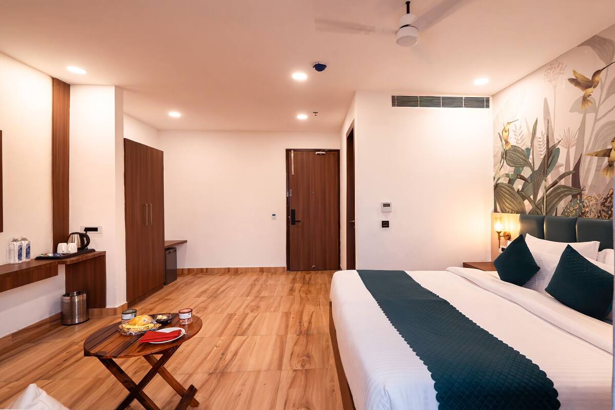 Una habitación de hotel con cama, una pequeña mesa con comida, un espejo, un armario y una puerta.
