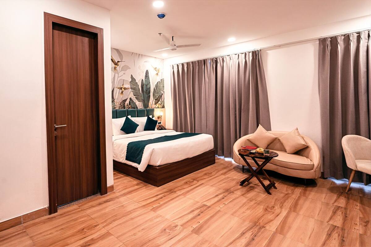 Un dormitorio con cama, sofá, mesita, ventilador de techo y una puerta.