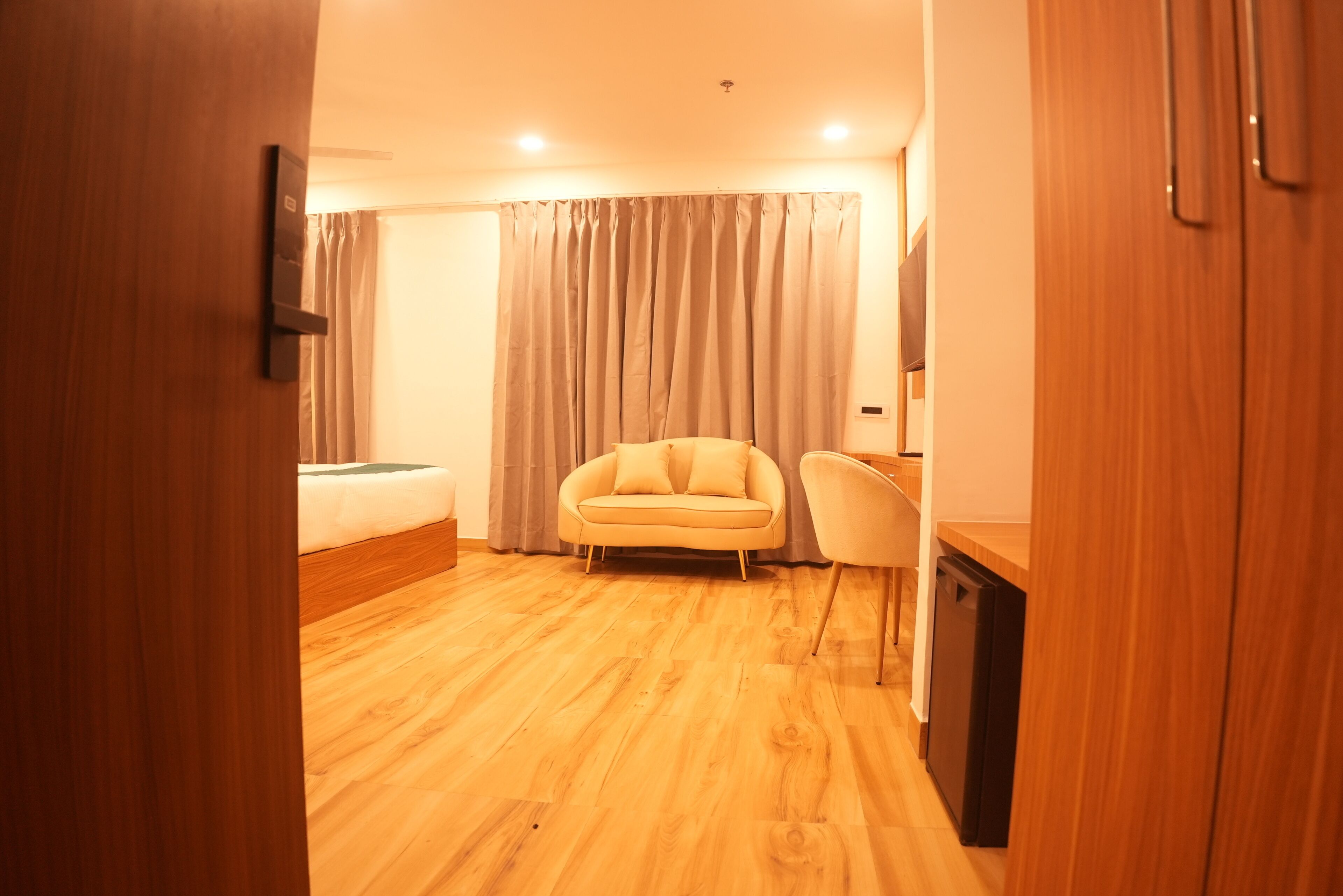 Habitación de hotel con piso de madera, cama, sofá, escritorio y una silla.