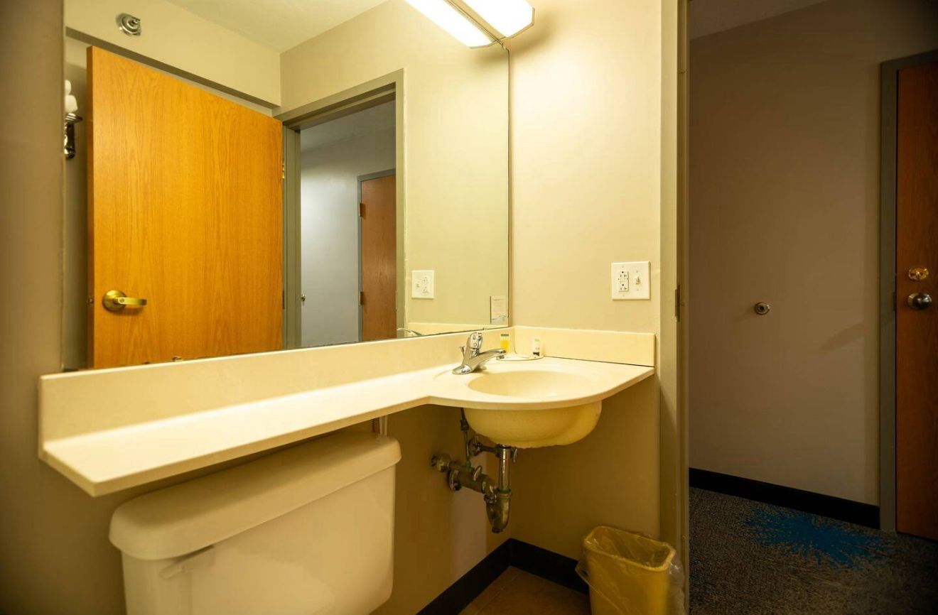 A bathroom with a sink, mirror, and toilet.