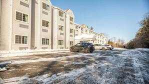 Un immeuble à plusieurs étages avec un parking situé devant.