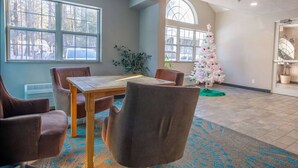 Une pièce comprenant une table à manger, des chaises, un sapin de Noël et de grandes fen êtres.