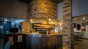 A bar area with a stone pillar, shelves with bottles, and a counter with a cash register. - Hotel El Toro  (Magdalena de Kino)
