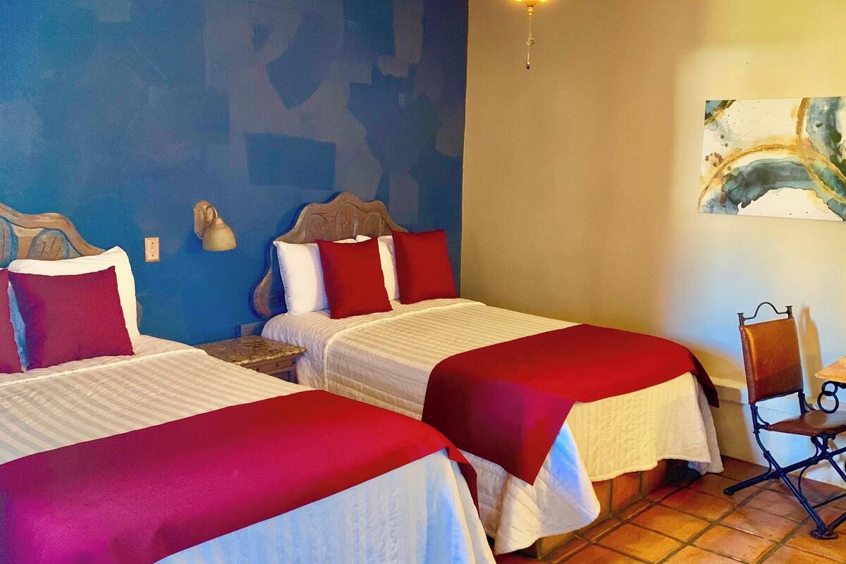 Una habitación de hotel con dos camas, un ventilador de techo y un cuadro en la pared.