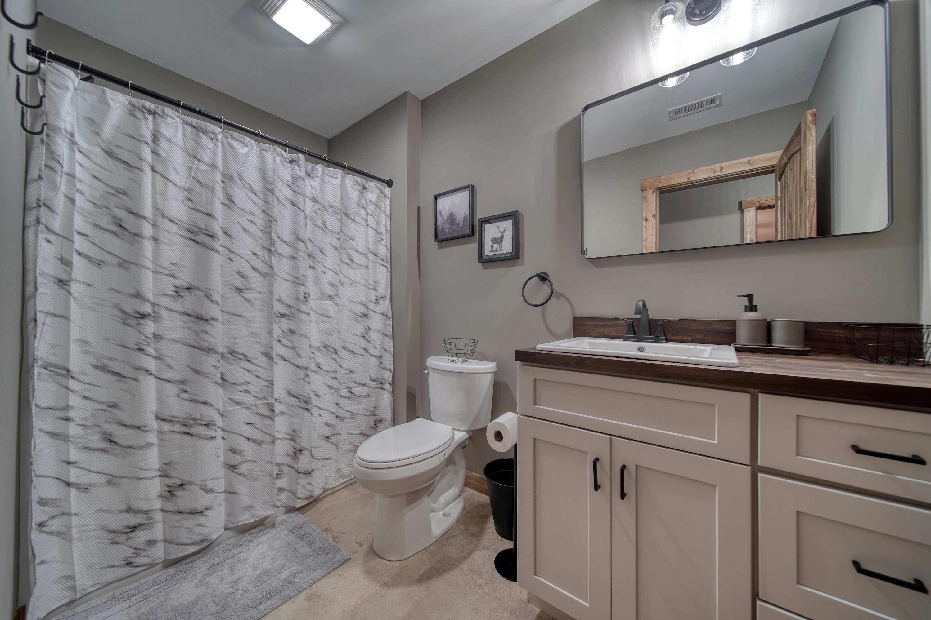 Een badkamer met toilet, wastafel, spiegel en douchegordijn.