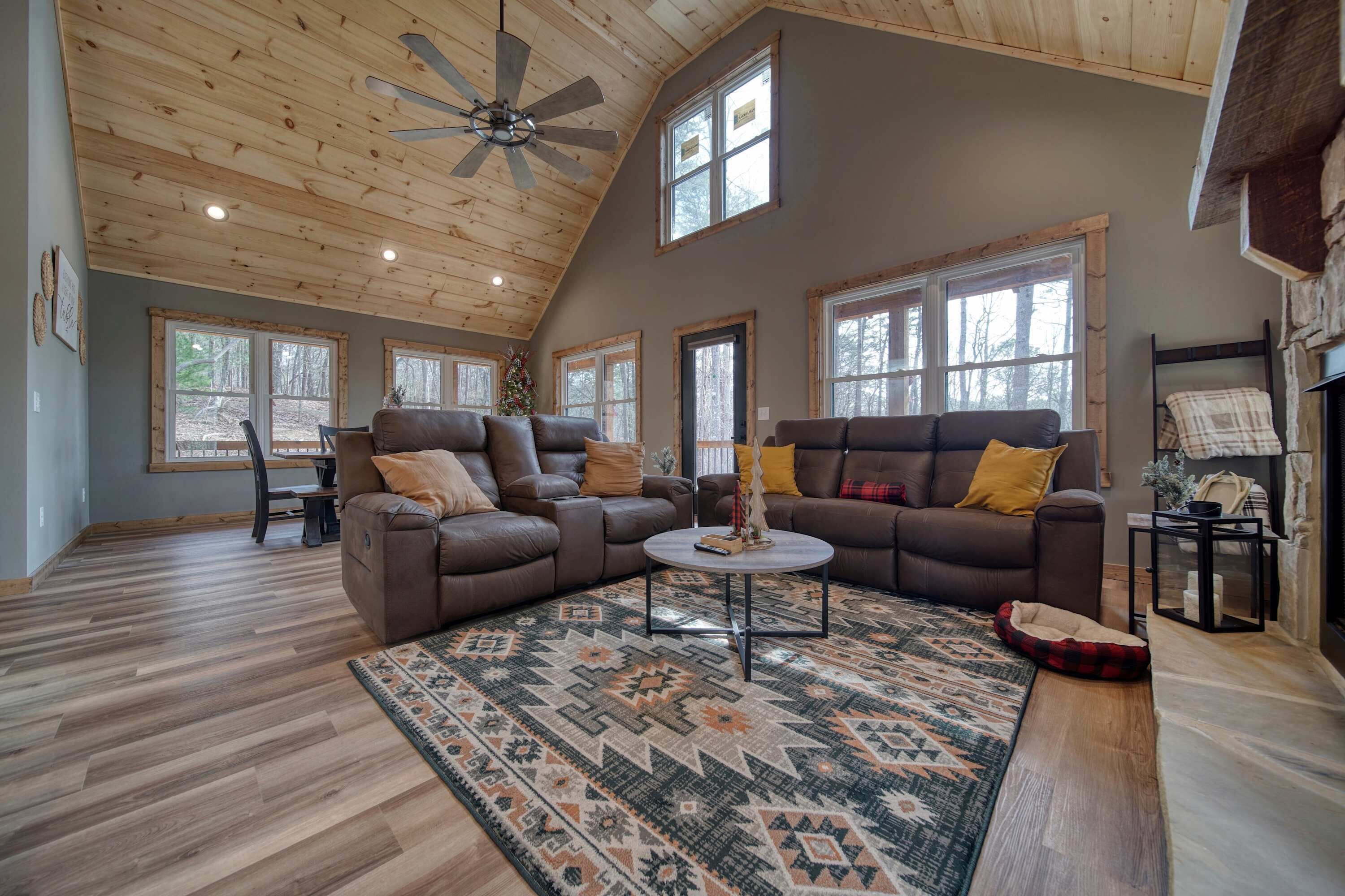 A spacious living room with a high ceiling, large windows, and a cozy fireplace.