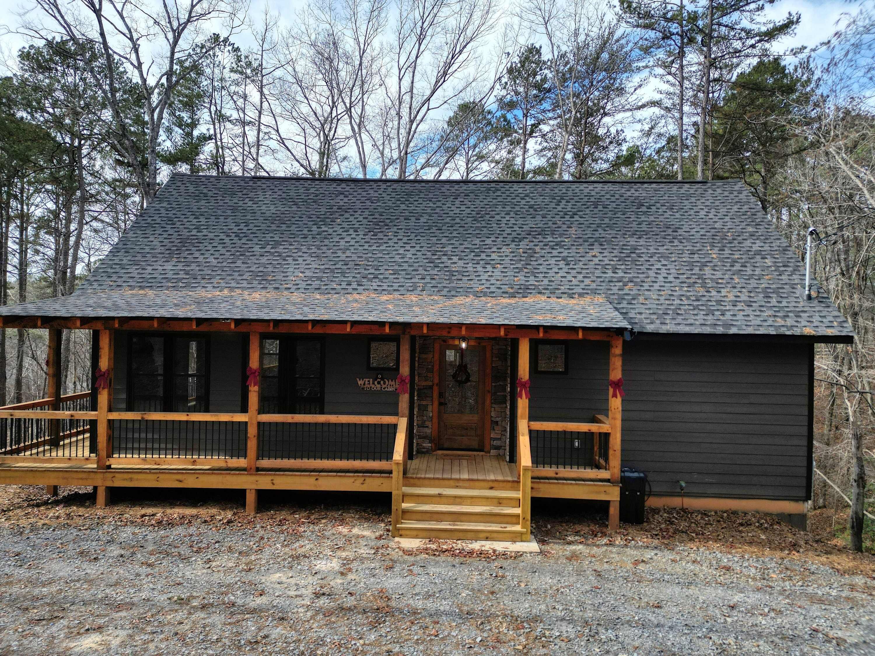 A cabin with a porch, wooden steps, and a stone foundation.