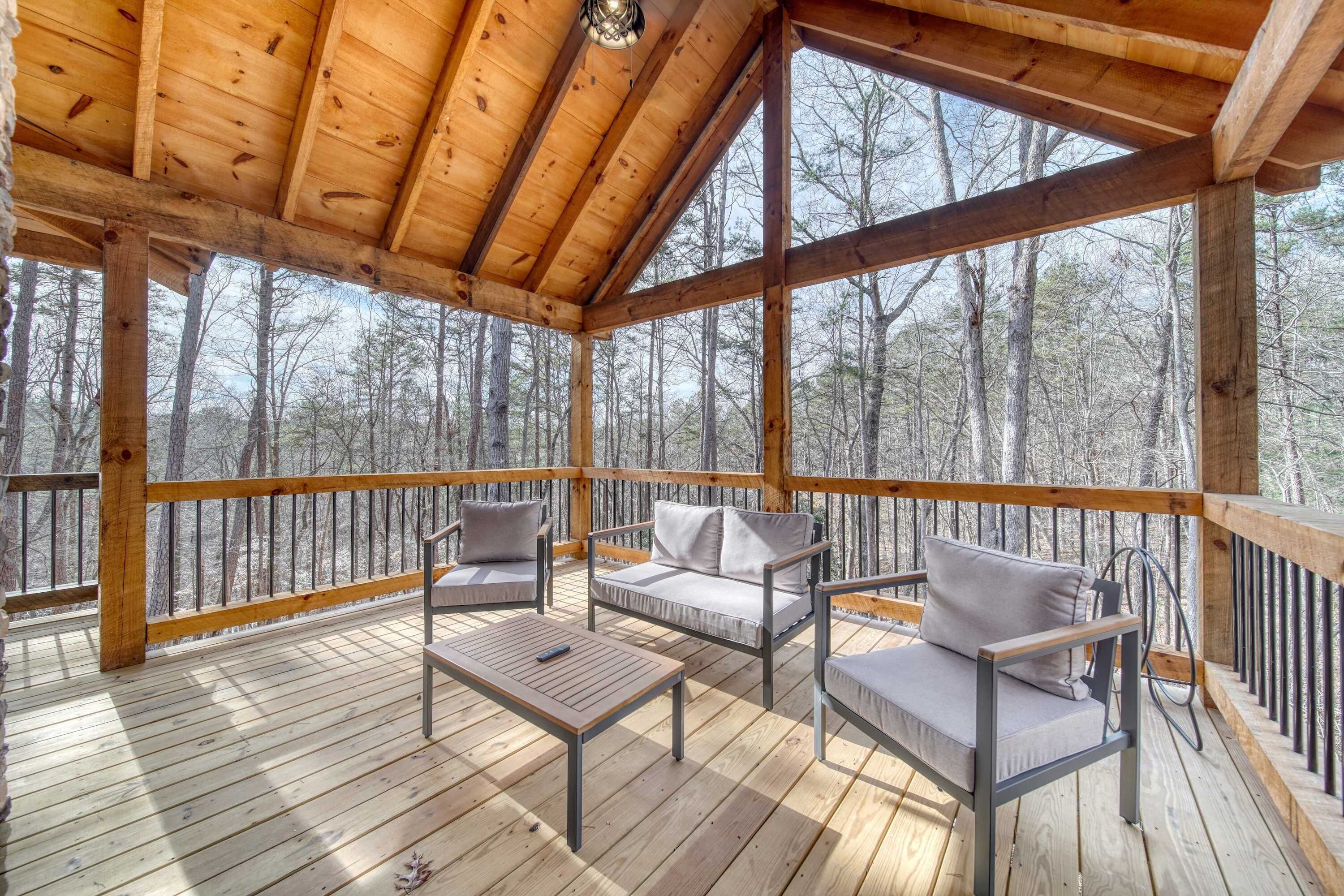 A wooden deck with a covered area, furnished with a sofa and two chairs, and a table.