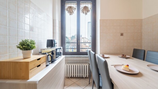 Een moderne keuken met een eethoek, voorzien van een houten aanrecht, een potplant, een radiator en een uitzicht door een raam.