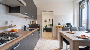 Een moderne keuken met een gasfornuis, donkere kastjes en een eethoek met een tafel gedekt voor twee personen.