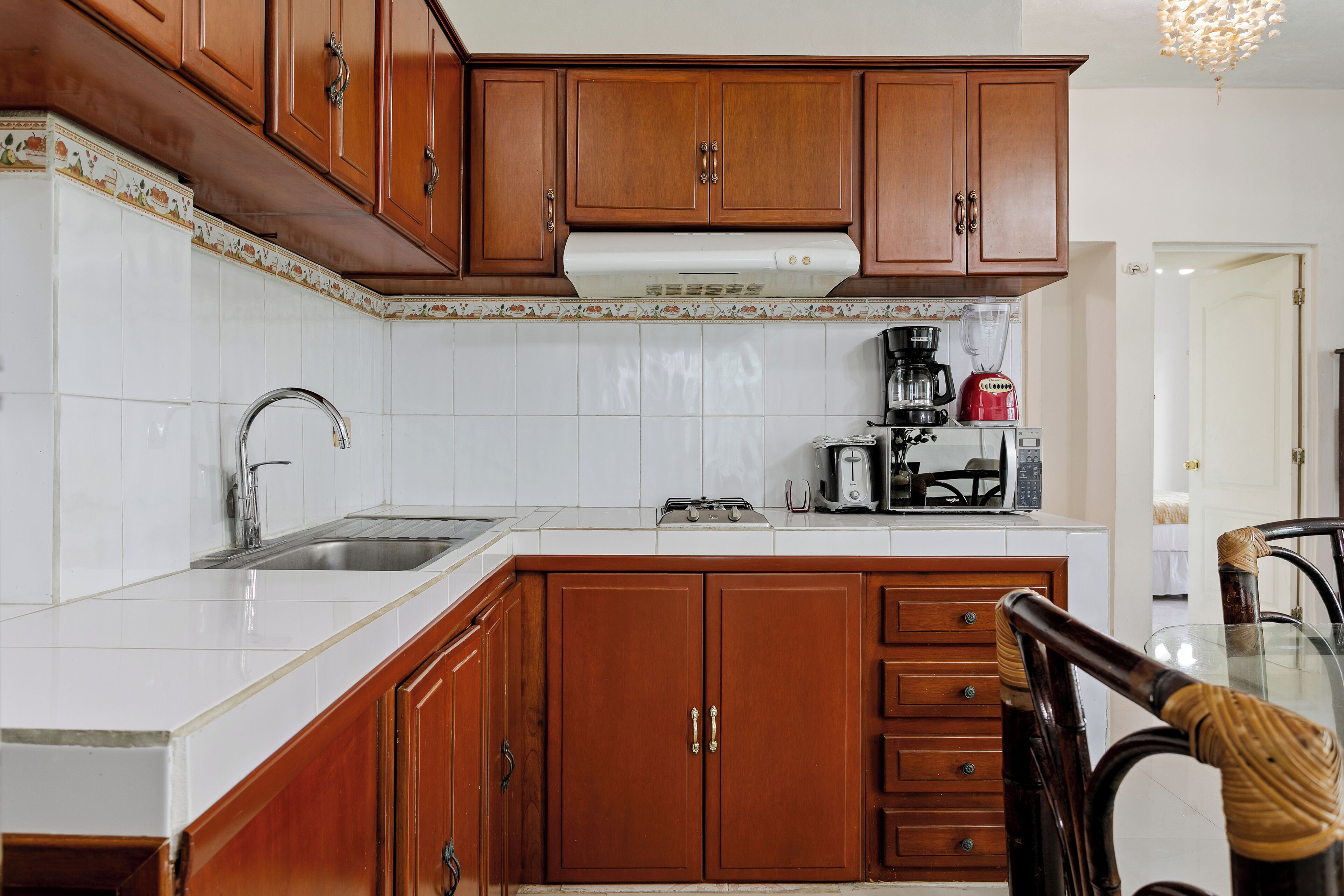 A kitchen with wooden cabinets, a white countertop, a sink, a stove, and a coffee maker.