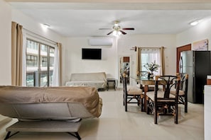A living room with a sofa, dining table, chairs, a ceiling fan, and a TV mounted on the wall. - Mar y Luna Department (playa del carmen)
