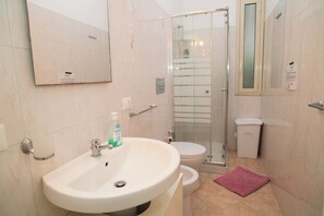 Ein Badezimmer mit Waschbecken, Toilette und Duschkabine aus Glas.