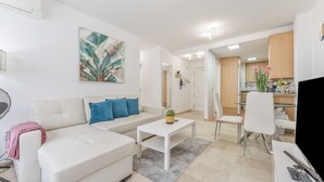 Una sala de estar moderna con un sofá blanco, una mesa de centro y un comedor con una mesa de vidrio y sillas.