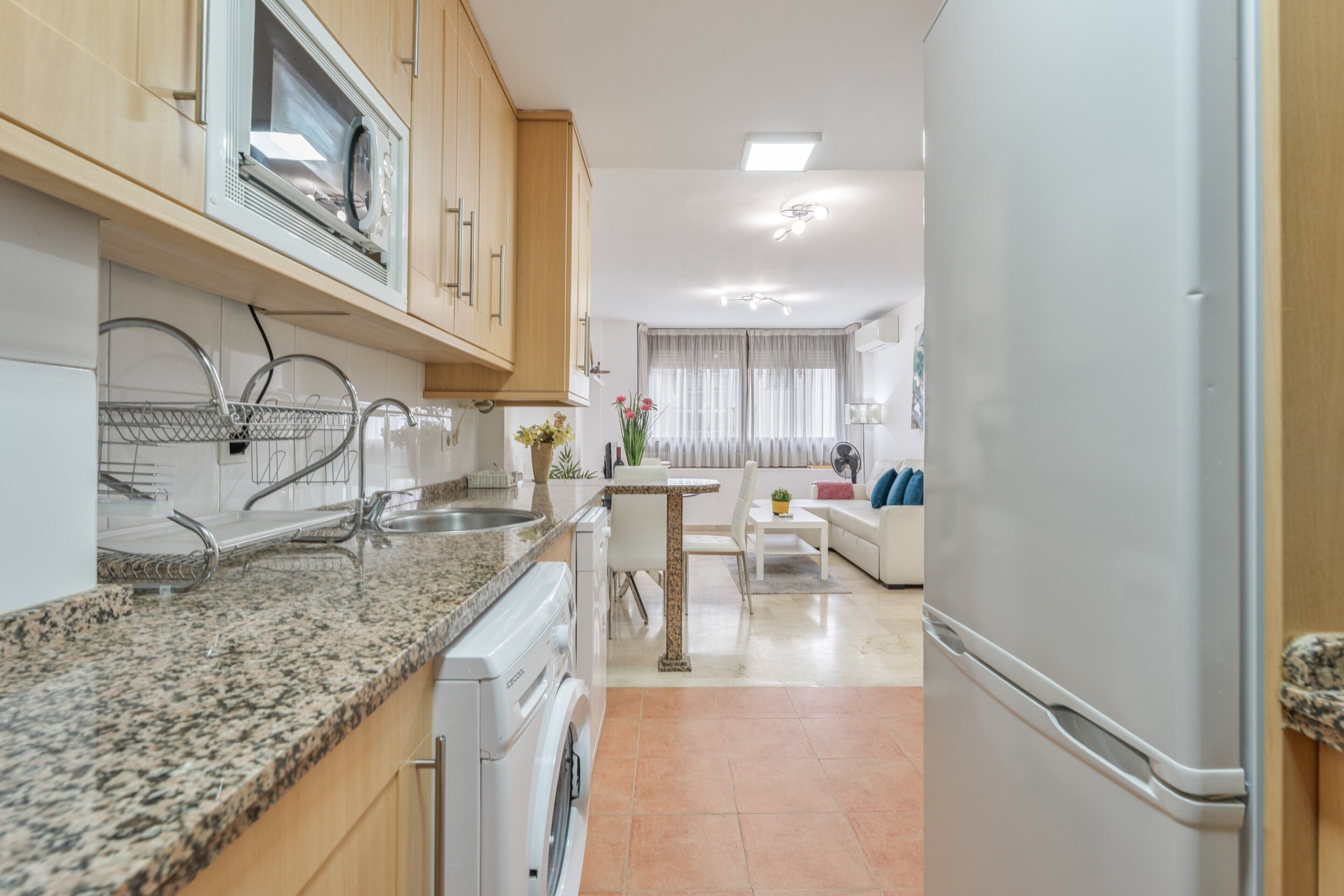 Una cocina moderna con encimeras de granito, horno empotrado y refrigerador.
