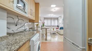 Una cocina moderna con encimeras de granito, horno empotrado y refrigerador.