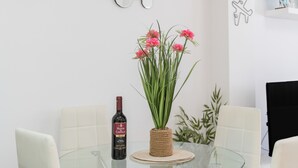 Una mesa de comedor con una botella de vino, un jarrón con flores y una planta.