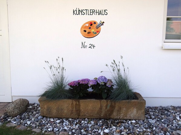 A building facade with a sign reading "KÜNSTLERHAUS Nr. 24" and a painted palette with a paintbrush. - Reethus for 6 adults & 2 small children, 3 bedrooms, 2 bathrooms, garden, sauna, fireplace, fenced (Zempin)