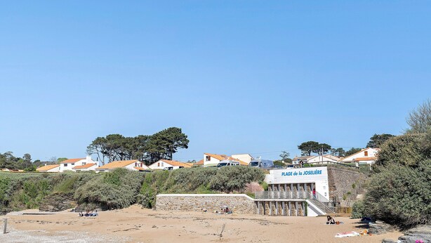 Une zone côtière comprenant des bâtiments, une plage et un panneau indiquant « PLAGE de la JOSELIÈRE ».