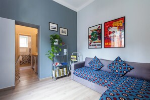 A modern living room with a grey sofa, patterned cushions, a bookshelf, and two framed pictures on the wall. - Materdei Terrace - One Bedroom Apartment, Sleeps 4 (Naples)