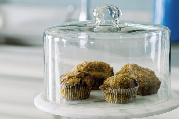 Una cúpula de cristal transparente cubre un expositor de mármol con varios muffins.