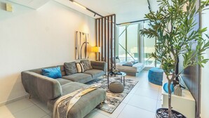 En moderne stue med en grå sofa, et sofabord og en potteplante.