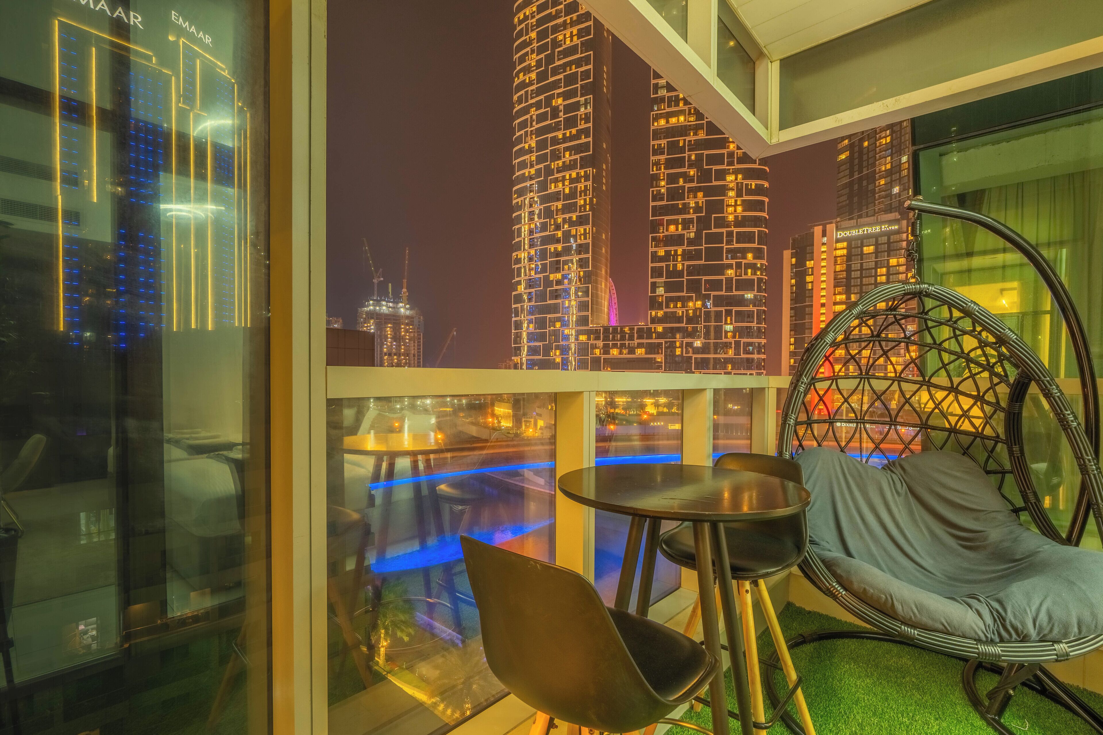 A modern room with a city view, a comfortable chair, a small table, and a glass partition.