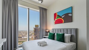 A hotel room with a large bed, grey curtains, a city view, and a colorful abstract painting. - Elegant 2Bed | Walk to Burj Khalifa & Dubai Mall (Downtown, Dubai)