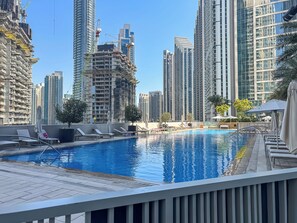 A rooftop pool with lounge chairs and a view of high-rise buildings, some under construction. - Elegant 2Bed | Walk to Burj Khalifa & Dubai Mall (Downtown, Dubai)