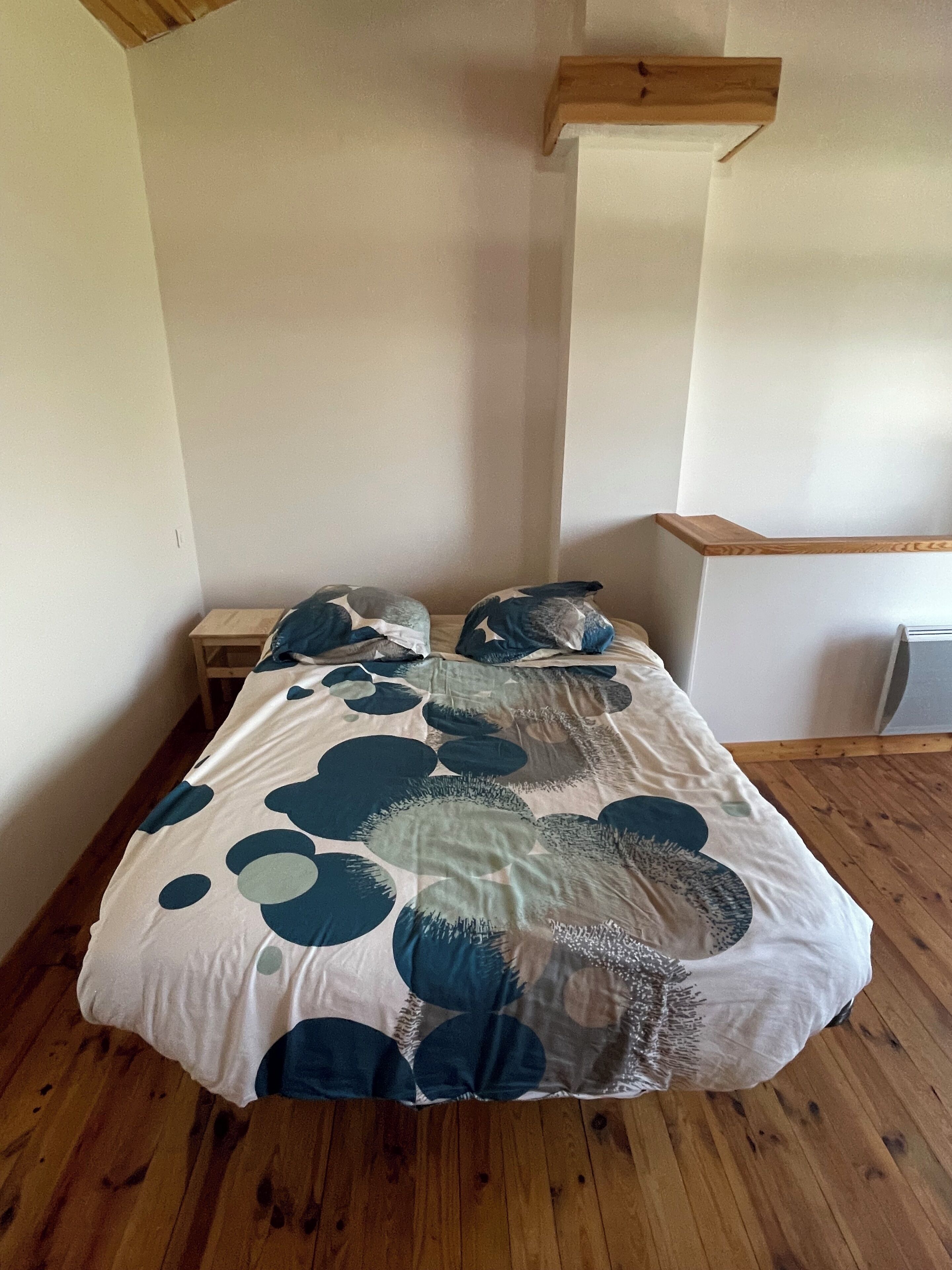 A bedroom with a bed, wooden headboard, and a nightstand.