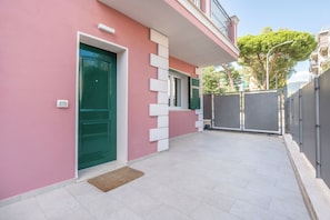 A modern building with a pink facade, a green door, and a gated entrance. - Aurea 27 - 5 Min Walk to Beach & Private Garden (Taggia)