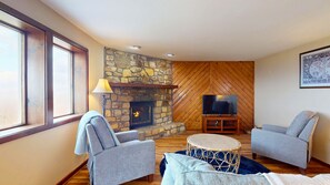 A cozy living room with a stone fireplace, a television, and two armchairs. - Crest 200I • Panoramic Mountain Views (Sugar Mountain)