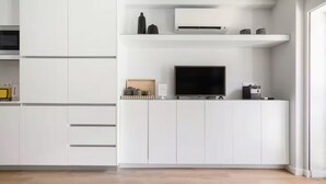 Eine moderne Küche mit weißen Schränken, einem Flachbildfernseher und einer eingebauten Klimaanlage.
