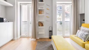 Ein modernes Schlafzimmer mit einem Bett, einer Couch, einem Bücherregal und einem Fenster mit Vorhängen.