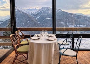 Una mesa de comedor con sillas y vistas a montañas nevadas.