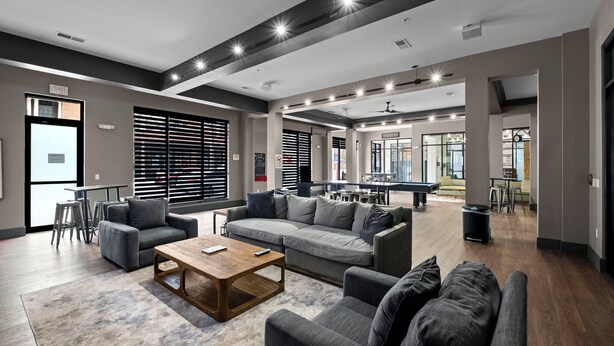 A spacious lounge area with a pool table, sofas, and a coffee table.