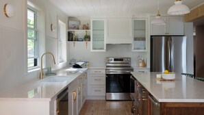 Une cuisine moderne avec des meubles blancs, des appareils en acier inoxydable et un grand îlot central.