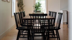 Un coin repas avec une table et des chaises en bois, un luminaire suspendu et une fenêtre donnant sur un paysage verdoyant.