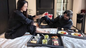Una habitación de hotel moderna con una cama, una bandeja de aperitivos y un televisor al fondo.