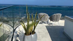 Un balcone con piante in vaso, una sedia e vista sull'oceano.