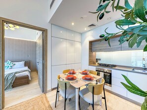 A modern kitchen with a dining area, a built-in stove, and a large window. - Super Luxury Flat Design with Sea View (Dubai)