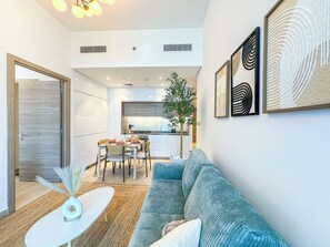 A modern living room with a sofa, a coffee table, and a dining area with chairs and a table. - Super Luxury Flat Design with Sea View (Dubai)