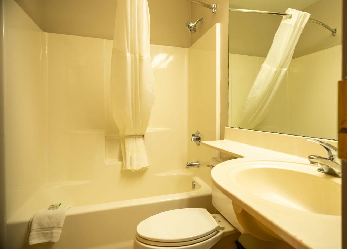 A bathroom with a bathtub, toilet, sink, and a mirror.