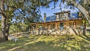 Una cabana rústica amb façana de pedra, un porxo cobert i vistes a una muntanya.